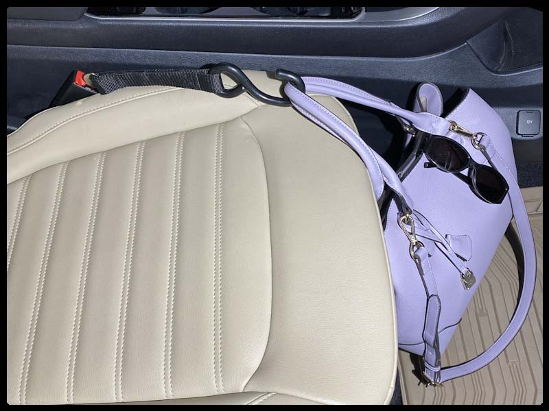 Large, light blue pocketbook suspended over seat, secured by a Hook & Go inserted into the front passenger seat belt buckle