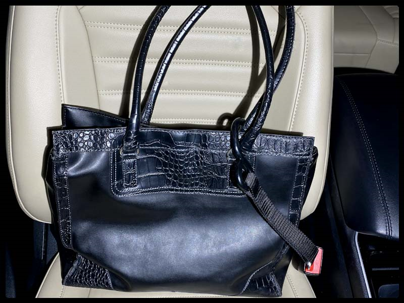 Large black bag on seat secured by a Hook & Go inserted into the front passenger seat belt buckle